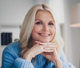 a woman with blonde hair posing in a blue knit sweater
